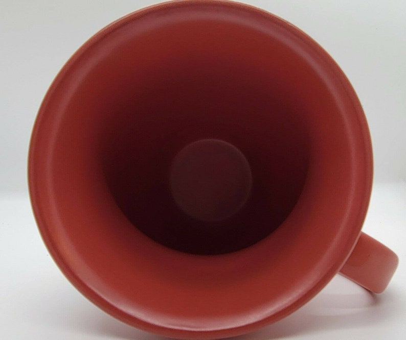 May include: A red ceramic mug with a smooth, glossy finish. The inside of the mug is also red.