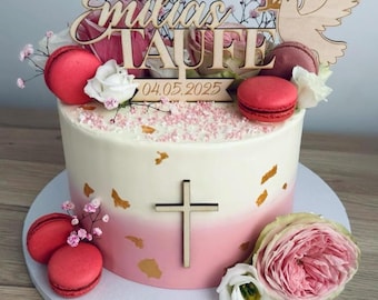 Könnte beinhalten: Zweistöckige Torte mit weißem und rosa Ombre-Frosting, verziert mit Makronen, Blumen und einem Holzkreuz. Die Torte ist mit einem Holzschild mit der Aufschrift "Emilias Taufe" und dem Datum "04.05.2025" versehen.
