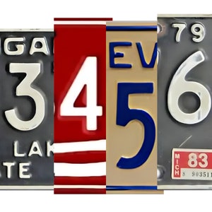 K&ouml;nnte beinhalten: Nahaufnahme von drei alten Nummernschildern mit den Zahlen 3456. Das erste Schild ist grau mit wei&szlig;en Buchstaben und lautet "MICHIGAN" und "LAKE STATE". Das zweite Schild ist rot, wei&szlig; und blau mit der Zahl "4". Das dritte Schild ist beige mit blauen Buchstaben und lautet "EVE". Das vierte Schild ist grau mit wei&szlig;en Buchstaben und lautet "79" und "MICH 8 90351".
