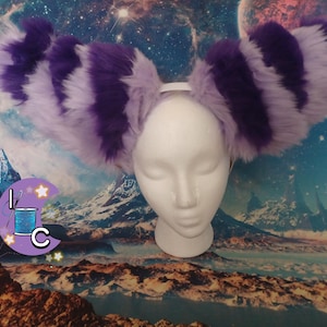 May include: Purple and white striped furry cat ears headband. The headband is white and the ears are fluffy and soft.