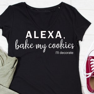 Puede incluir: Camiseta negra con cuello en V con el texto "ALEXA, bake my cookies I'll decorate" en escritura blanca. La camiseta se combina con pantalones verde oliva y una zapatilla roja.