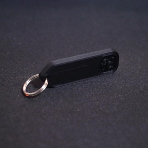 May include: A black plastic key chain with a silver metal ring.