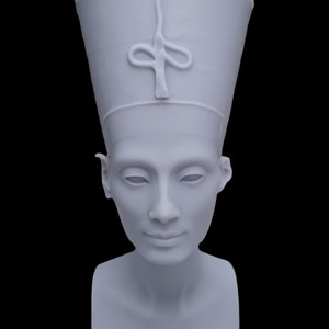 Pode incluir: Busto cinza claro de Nefertiti, com um chapéu alto e cilíndrico com um emblema estilizado. A escultura retrata um rosto sereno com os olhos fechados e uma superfície lisa e sem adornos. O busto está sobre um fundo preto.