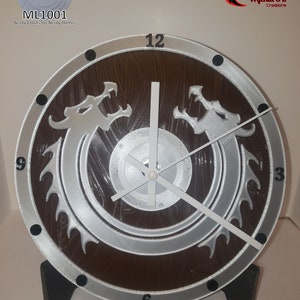 May include: A brown and silver clock with a dragon design. The clock has a wooden base and a white face with black numbers. The clock is labeled "ML1001 Nerdy Clocks for Nerdy Homes" and "Wyckid 3D Creations".