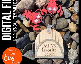 May include: A wooden keychain featuring a lobster design and the text "PAPA'S favourite catch." Two red lobster charms are attached to a wooden arch. The text "DIGITAL FILE NO PHYSICAL ITEM WILL BE SENT" is on the left side.
