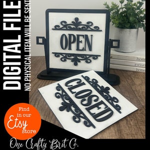 May include: A black and white sign with the words "OPEN" and "CLOSED" in a decorative font. The sign is on a black stand and has a white background.