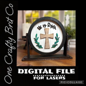 May include: A wooden sign with a black frame and a white background. The sign features a cross with a green leafy wreath around it and the text "He is Risen".