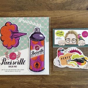 May include: A set of patches and stickers featuring a retro-style design. The patches include a purple and orange hairspray can and a cloud of hairspray. The stickers include a woman with glasses and birds, and other colorful bird designs.