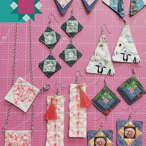 May include: A selection of handmade paper pieced earrings and a necklace, presented on a pink cutting mat. The earrings showcase diverse geometric designs and patterns, some with tassels. The text "PAPER PIECED JEWELRY Carolina Moore" is visible.