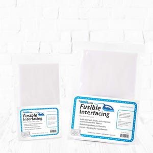 Peut inclure: Deux paquets d'entoilage thermocollant blanc, étiquetés "Fusible Interfacing" par annie.com. Les étiquettes sont blanches avec des bordures et du texte bleus, et comprennent des instructions et des détails sur le produit. Un paquet est de 1 yard, l'autre de 5 yards.