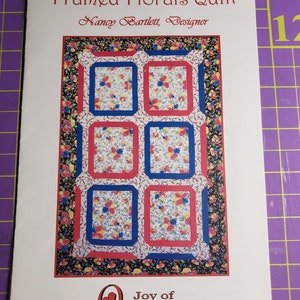 May include: A quilting pattern booklet featuring a colourful floral quilt design on the cover. The title is "Framed Florals Quilt" and the designer is "Nancy Bartlett". The booklet is from "Joy of Quilting".