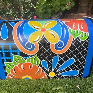 May include: A blue mailbox with a colorful floral design. The mailbox is painted with orange, yellow, green, and blue flowers on a black background.