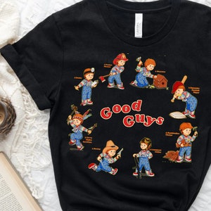 May include: Black t-shirt with a graphic of eight Good Guys dolls from the Child's Play movie franchise. Each doll is depicted in a different pose, holding a tool or weapon. The text "Good Guys" is printed in red and white letters.