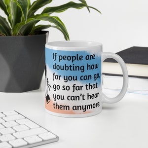 May include: White ceramic mug with a blue and orange watercolor background. The mug features the text "If people are doubting how far you can go, go so far that you can't hear them anymore."
