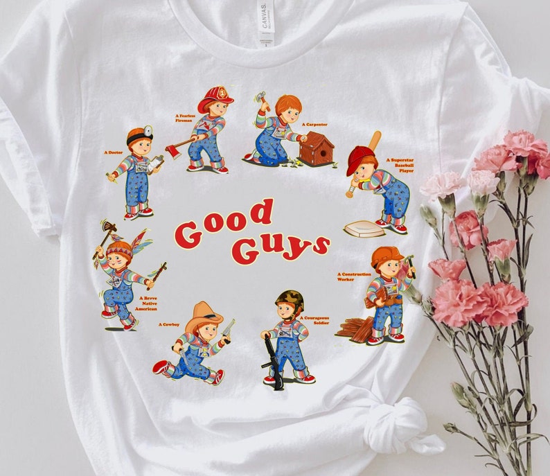 May include: White t-shirt with a graphic of a group of children dressed as different professions. The text "Good Guys" is printed in red and orange letters.
