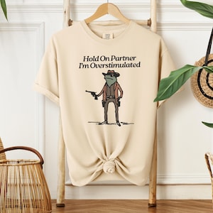 Hold On Partner, I&#39;m Overstimulated T-Shirt | Whimsical Cowboy Frog T-Shirt | Funny Tees, Unisex Graphic Tee, Casual Wear, Gift for Him/Her