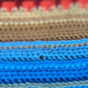 Puede incluir: Primer plano de una tela de punto con rayas de hilo rojo, naranja, beige, azul y verde.