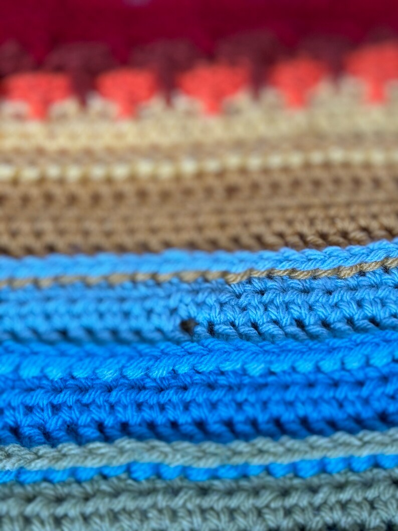 Puede incluir: Primer plano de una tela de punto con rayas de hilo rojo, naranja, beige, azul y verde.