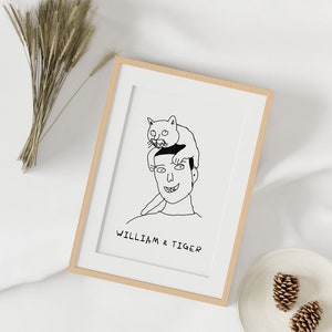 K&ouml;nnte beinhalten: Eine Schwarzwei&szlig;-Zeichnung einer Person mit einer Katze, die auf ihrem Kopf sitzt. Die Zeichnung ist in einem hellen Holzrahmen gerahmt. Der Text "William & Tiger" befindet sich unter der Zeichnung.
