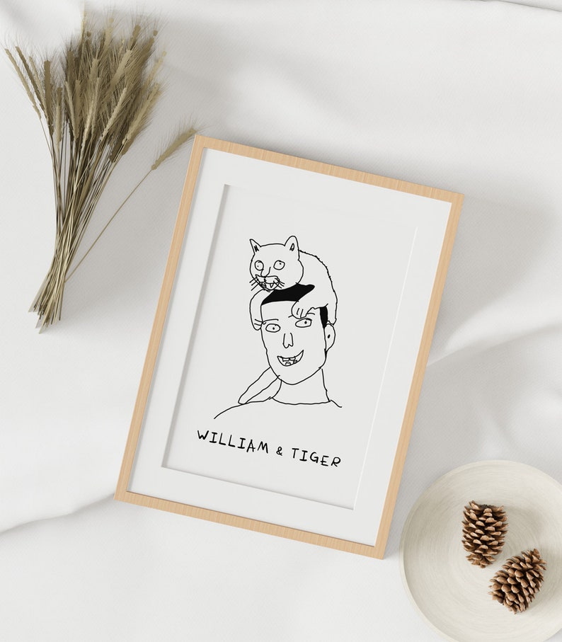 K&ouml;nnte beinhalten: Eine Schwarzwei&szlig;-Zeichnung einer Person mit einer Katze, die auf ihrem Kopf sitzt. Die Zeichnung ist in einem hellen Holzrahmen gerahmt. Der Text "William & Tiger" befindet sich unter der Zeichnung.
