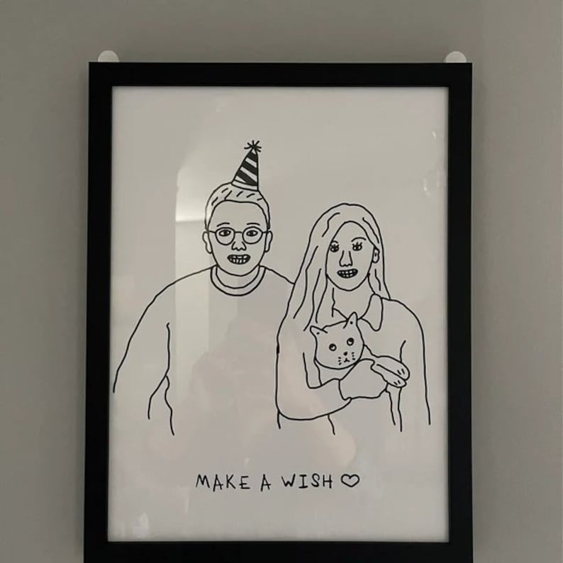K&ouml;nnte beinhalten: Schwarz-wei&szlig;-Zeichnung eines Paares mit einer Katze. Der Mann tr&auml;gt eine Partym&uuml;tze und die Frau h&auml;lt die Katze. Der Text "MAKE A WISH" befindet sich unter der Zeichnung.
