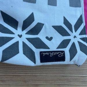 Puede incluir: Bolsa de lona blanca con un patr&oacute;n geom&eacute;trico blanco y negro y una etiqueta negra que dice "Remarkable".