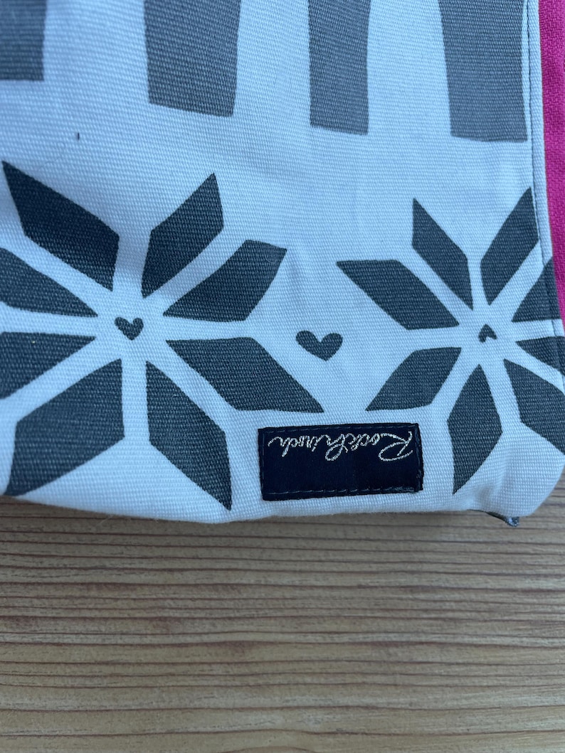 Puede incluir: Bolsa de lona blanca con un patr&oacute;n geom&eacute;trico blanco y negro y una etiqueta negra que dice "Remarkable".