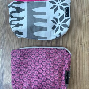 Puede incluir: Dos estuches con cremallera con diferentes patrones. El estuche superior es blanco con dise&ntilde;os geom&eacute;tricos negros y una cremallera rosa. El estuche inferior es rosa con un patr&oacute;n floral negro. Ambos estuches tienen una etiqueta negra con el texto "Rooster & Hen" en ellos.