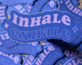 May include: A close-up of a blue sticker with the words "inhale exhale" in a light purple font. The sticker has a sparkly design on each side.