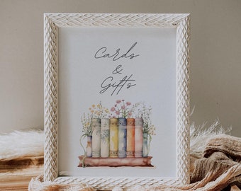 May include: A framed print with the words "Cards & Gifts" in elegant script. The artwork features a row of colorful books with flowers in vases. The frame is white with a textured design, set on a wooden tray with a draped fabric.
