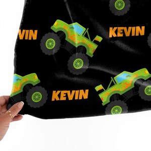 Może przedstawiać: Czarny materiał z powtarzającym się wzorem zielonych monster truck&oacute;w z pomarańczowymi płomieniami i nazwą "Kevin" w pomarańczowym tekście.