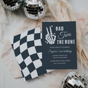Puede incluir: Una tarjeta con un patr&oacute;n de cuadros negros y blancos con una tarjeta de invitaci&oacute;n azul oscuro en la parte superior. La tarjeta de invitaci&oacute;n tiene una mano de esqueleto blanca haciendo un signo de paz con el texto "Bad Two The Bone" y detalles para una fiesta de cumplea&ntilde;os de 2 a&ntilde;os.
