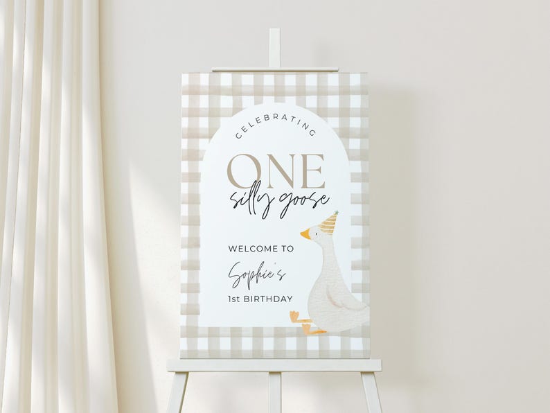 May include: A brown and white gingham patterned sign with the text "Celebrating One Silly Goose" and "Welcome to Sophie's 1st Birthday". A cartoon goose with a yellow party hat is on the sign.