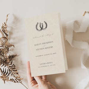 Peut inclure: Une invitation de mariage au design rustique avec deux fers à cheval entrelacés. L'invitation est pour Bailey Thompson et Stetson Rogers, et elle indique que le mariage aura lieu le samedi 31 août 2024 à l'hôtel Liceria.