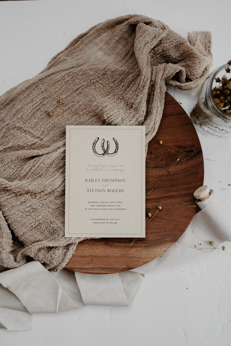 May include: A wedding invitation with a rustic theme. The invitation features two horseshoes intertwined and the text "We invite you to celebrate our marriage" in cursive. The names Bailey Thompson and Stetson Rogers are printed in a bold font. The date and time of the wedding are listed as Saturday, August Thirty-first, Two Thousand Twenty-Five at Half Past Four in the Afternoon. The location is listed as 123 Anywhere St, Any City. The invitation concludes with "Reception to Follow."
