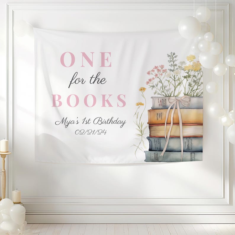 May include: White banner with pink text that reads "ONE for the BOOKS" and "Mya's 1st Birthday 02/21/24". A stack of books with a floral arrangement on top is on the right side of the banner.