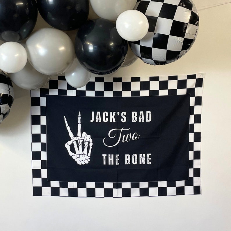 May include: Black and white checkered banner with the text "Jack's Bad Two The Bone" and a white skeleton hand making a peace sign.
