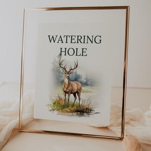 May include: A framed watercolor painting of a deer standing in a forest clearing with the text "WATERING HOLE" above it.