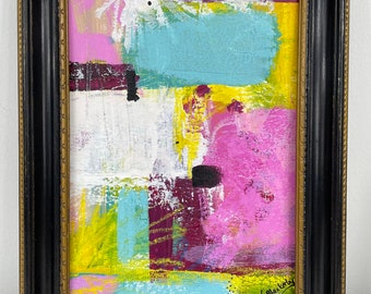 May include: Abstract painting in a black frame with a gold trim. The painting features bright colors including pink, yellow, blue, green, and white. The artist's signature, "Linda Blackarty", is visible in the bottom right corner.