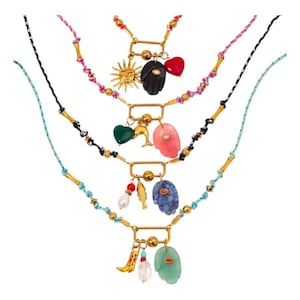 May include: Four colorful necklaces with gold-tone metal accents and various charms. Charms include a sun, heart, hand, dolphin, and gemstones. The necklaces have woven cords in black, pink, and blue, with gold-colored bamboo-style beads.