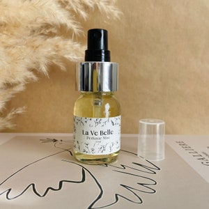 May include: A clear glass bottle with a silver cap and black spray nozzle. The bottle contains a light yellow liquid and has a white label that reads "La Ve Belle Perfume Mist 30ml".