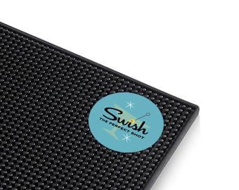 May include: Black bar mat with a blue circle featuring the text "Swish The Perfect Shot" in a retro font. The circle also has a white star and a yellow needle.