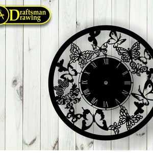 May include: Black clock face with Roman numerals and a decorative design of butterflies around the edge. The clock is on a white wood background.