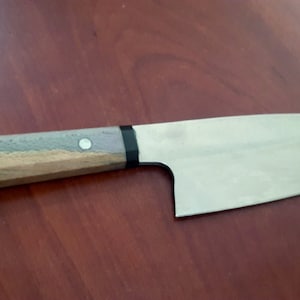 May include: A small, stainless steel kitchen knife with a wooden handle. The handle is a light brown color with a dark brown and gray pattern. The knife has a black ring around the handle.