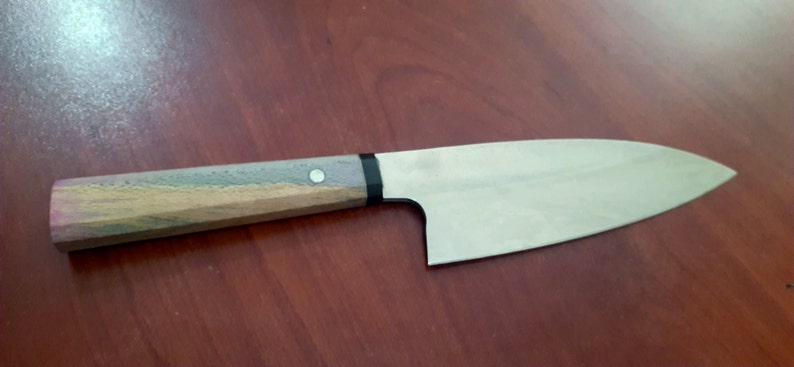 May include: A small, stainless steel kitchen knife with a wooden handle. The handle is a light brown color with a dark brown and gray pattern. The knife has a black ring around the handle.