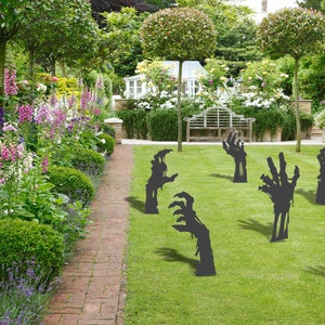 Könnte beinhalten: Ein Set mit acht schwarzen Zombie-Hand-Garten-Dekorationen. Die Hände sind so positioniert, als würden sie aus dem Boden ragen. Die Dekorationen sind auf einem Rasen platziert.