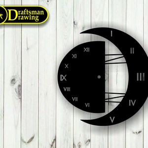 Puede incluir: Cara de reloj de metal negro con forma de media luna con marcas de números romanos. La cara del reloj está sobre un fondo de madera blanca.