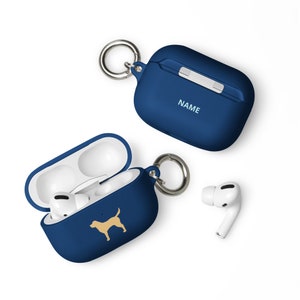 Puede incluir: Una funda de silicona azul para AirPods con una silueta de perro dorada y un mosquetón plateado. La funda está abierta y los AirPods están dentro. La funda tiene la palabra "NAME" impresa en la parte delantera.