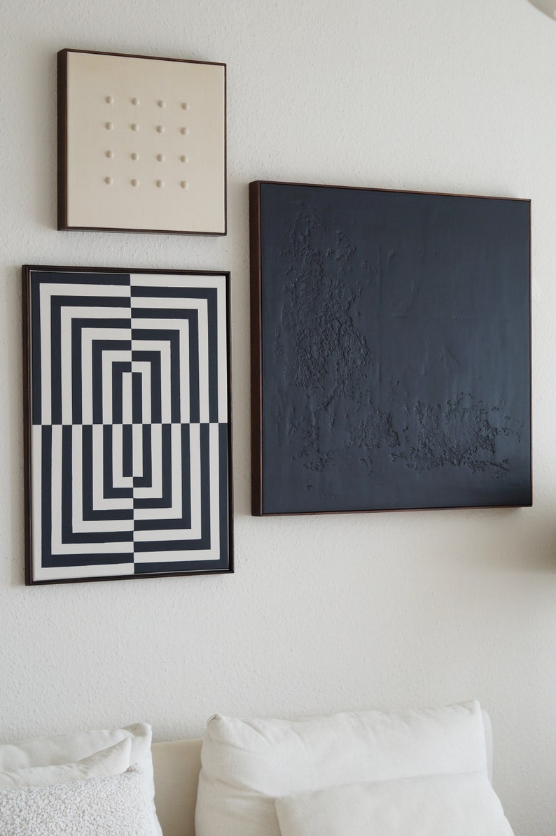 Pu&ograve; includere: Tre dipinti astratti incorniciati su una parete bianca. I dipinti sono in nero, bianco e grigio. I dipinti sono di dimensioni e forme diverse. I dipinti sono appesi a una parete bianca.