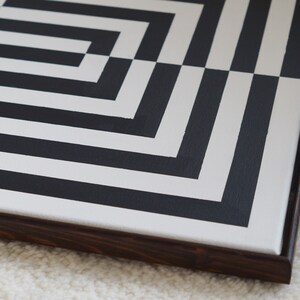 Pu&ograve; includere: Un dipinto astratto geometrico in bianco e nero su tela con una cornice in legno scuro.